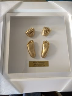 three gold baby feet in a white frame