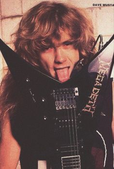 a man sticking his tongue out while holding an electric guitar in front of his face