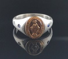 Handmade Miraculous Medal Virgin Mary Medal Ring with 2 sapphires. Ring itself is made out of sterling silver and medal is 14K yellow gold filled. Adorned with 2 sapphires.  Check me out on Instagram @anaraandco for shop updates, news, discounts and creative process. ❖ U.S. Size 7 approximate ❖ Sterling silver ❖ 14K gold filled Virgin Mary Medal ❖ Sapphires  ❖ Hand fabricated, oxidized, polished Red box on the picture is not included. Will come in a simple ring holder box. Shipping is 1st class fully insured, upgrade is available. Shield Ring, Ring Sapphire, Simple Ring, Miraculous Medal, Rings Simple, Handmade Sterling Silver, Virgin Mary, Ring Holder, Signet Ring