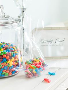 there are many different colored candies in the glass bowl on the table next to it