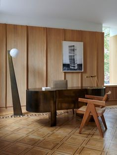 a room with wooden paneling and a desk in the center, along with two chairs