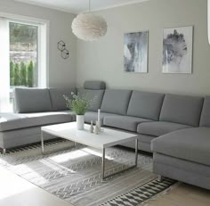 a living room with grey couches and white coffee table in front of large windows