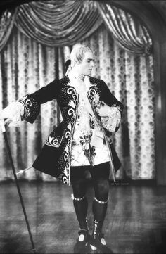 an old photo of a man dressed in costume and holding two canes on stage