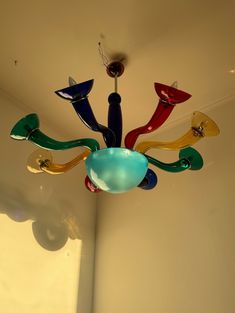 a multicolored glass chandelier hanging from the ceiling in a room with white walls