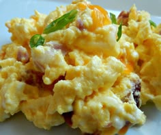 scrambled eggs with bacon and cheese on a white plate