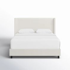 a bed with white sheets and pillows on it