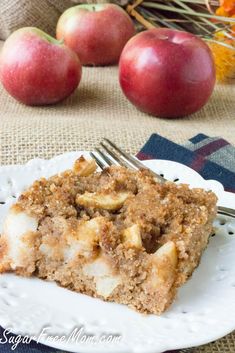 a piece of apple crumb cake on a plate with a fork and some apples in the background