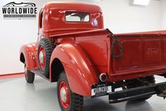 an old red truck parked in a garage