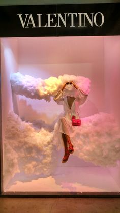 a display case with clouds and a woman in white