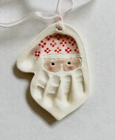 a white ceramic ornament with a santa clause on it's face and hands