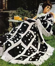 a woman sitting in a lawn chair with a blanket on top of her and a glass of orange juice