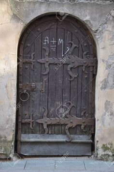 an old iron door on the side of a stone building with graffiti written on it