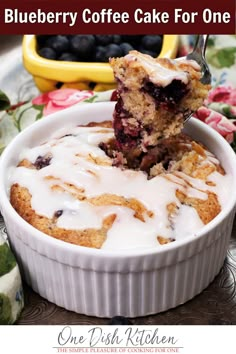 blueberry coffee cake for one is in a white dish with a bite taken out