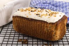 a loaf of cake with white frosting and sprinkles on a cooling rack