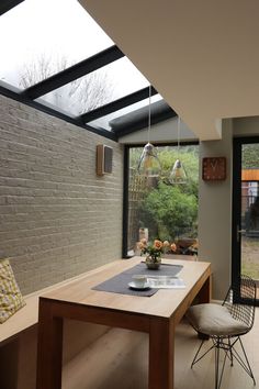 a dining room table with chairs and a bench in front of a large glass window