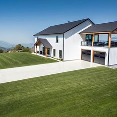 an aerial view of a modern house with large lawn and two garages on each side