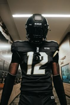 a football player in uniform walking down the hall with his hand on his hip and wearing a helmet