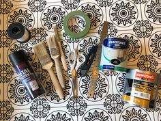 various crafting supplies laid out on top of a patterned wallpapered surface with scissors, tape and glue