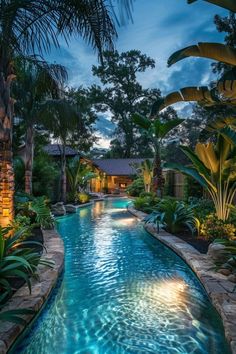 an outdoor swimming pool surrounded by palm trees and other greenery at night with lights on the water