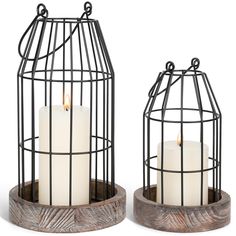 two candle holders with candles in them sitting on wooden bases and metal caged stands