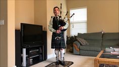 a man in a kilt playing bagpipes while standing in front of a tv