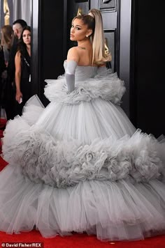 lady in white gown on red carpet with other people behind her wearing black and white