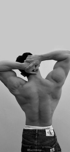 black and white photograph of a man with his back to the camera, holding his hands behind his head