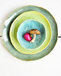 two green plates with food on them sitting next to each other in front of a white wall