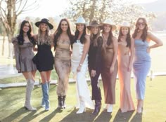 a group of women standing next to each other on top of a grass covered field