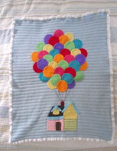 a crocheted blanket with a house and balloons attached to the back of it