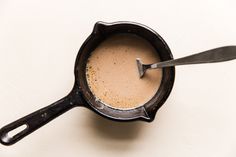 an old cast iron skillet with a spoon in it on a white table top