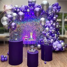 purple and silver balloons are on display in front of a backdrop with an arch made out of balls