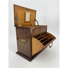 an old fashioned wooden box with drawers and keys in the bottom section is open to reveal its contents