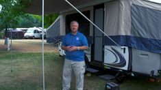 a man standing in front of a camper trailer with the door open and it's awning down