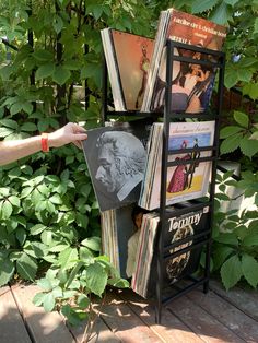 there is a magazine rack that has many magazines on it and someone holding one in the other hand