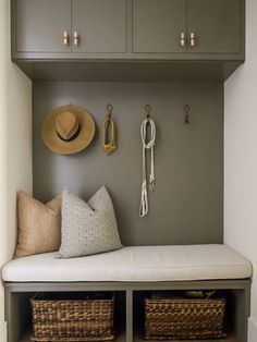 a bench with two baskets and hats on it in front of a wall mounted coat rack