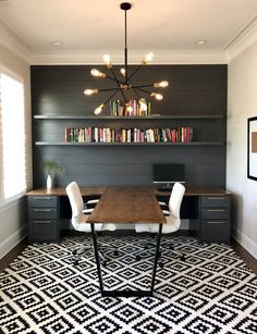 a room with a table, chairs and bookshelves on the wall above it