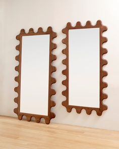 two mirrors sitting next to each other on top of a wooden floor in front of a white wall