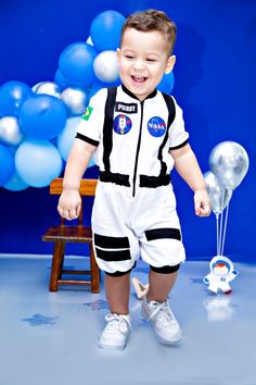 a little boy that is standing up in some kind of space suit with balloons behind him