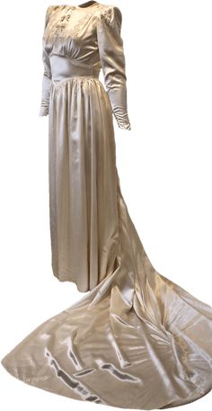 This dress is named Mary. Made of heavy cream colored silk, this sumptuous wedding gown is original from the early 1940s. Warn only once in 1941, this dress is in near perfect condition. lined up the back with thirty five silk covered buttons, decorated with delicate lace details, and lined down the front with three sweet bows, this dress is elegant and understated. With a long train, pointed cuffs, and stylized puff sleeves at the shoulders.• 24 inch waist• 26 inch sleeves• 17 and 1/2 inch back Silk Victorian Wedding Dress, Vintage Wedding Dress 1930s Silk Satin, Vintage Cream Satin Gown, 1940s Silk Dress, 24 Inch Waist, 1950s Cream Wedding Dress, Wedding Gowns With Sleeves, Cream Silk, Long Train