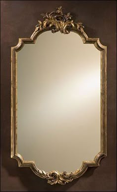 an ornate gold framed mirror against a brown wall