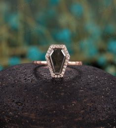 an engagement ring with a black diamond surrounded by white diamonds on top of a rock