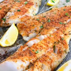 two fish fillets with lemons and parsley on the side, ready to be cooked