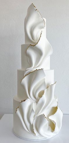 a three tiered cake with white icing and gold decorations on it's sides