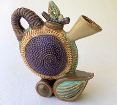 a ceramic teapot with a brass horn on it's head and two wheels