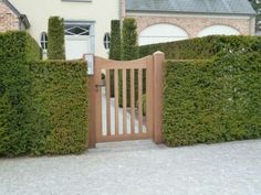 a house with a wooden gate surrounded by hedges