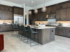 a large kitchen with lots of counter space and lights hanging from the ceiling over the island