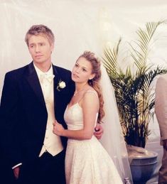 a young man and woman standing next to each other in front of a white backdrop