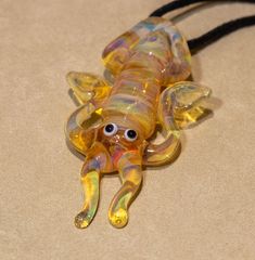 a glass figurine laying on top of a brown table next to a black cord