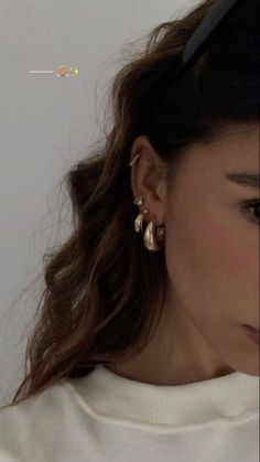 a close up of a person wearing earring's and a white sweater shirt